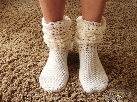 Cremefarbene gehäkelte Damensocken mit lockerem Rüschbündchen an Damenbeinen auf Teppichboden