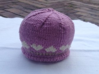 Lila gestrickte Babymütze mit heller Herzbordüre am Saum
