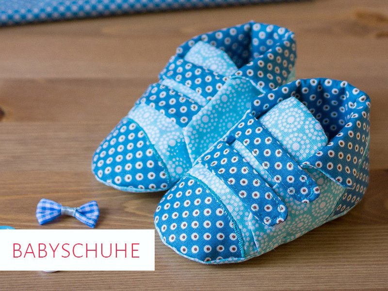 Paar blaue Babyschuhe aus Stoff mit Punktmuster und Verschlussriemen