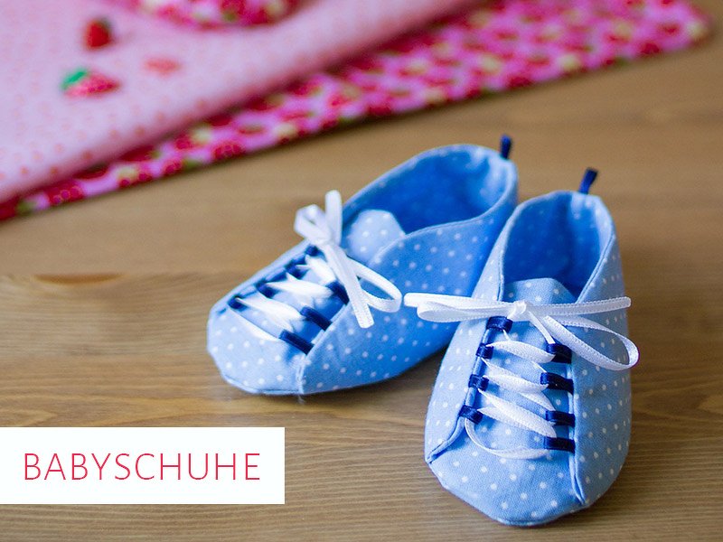 Blaue gepunktete Babyschuhe mit weißen Schnürsenkeln auf Holzuntergrund