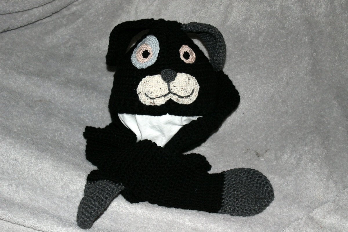 Gehäkelte schwarze Mütze mit Hundegesicht, weißer Schnauze und grauen Ohren.