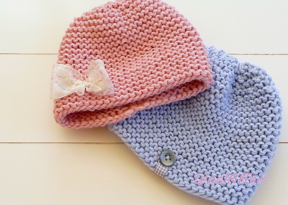 Rosa Babymütze mit Schleife und hellblaue Babymütze mit Knopf, beide im Krausmuster gestrickt.