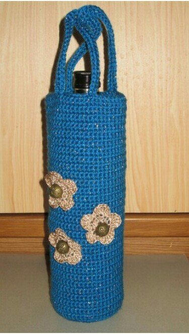 Handgehäkelte blaue Flaschenhülle mit zwei Griffen und drei beigen Blumenapplikationen