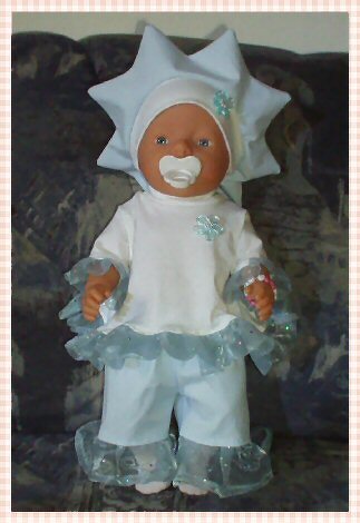 Stoffpuppe in einem hellblauen und weißen Outfit mit Rüschen, Hose und sternförmiger Haube, dazu Schnuller.