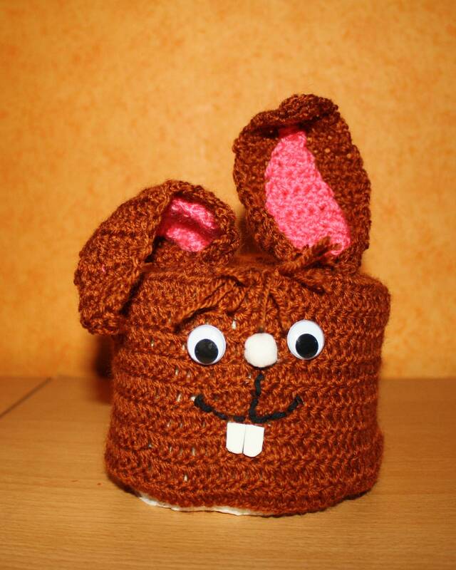 Braune gehäkelte Hülle mit Hasenohren, rosa Innenohren, Wackelaugen und weißen Vorderzähnen