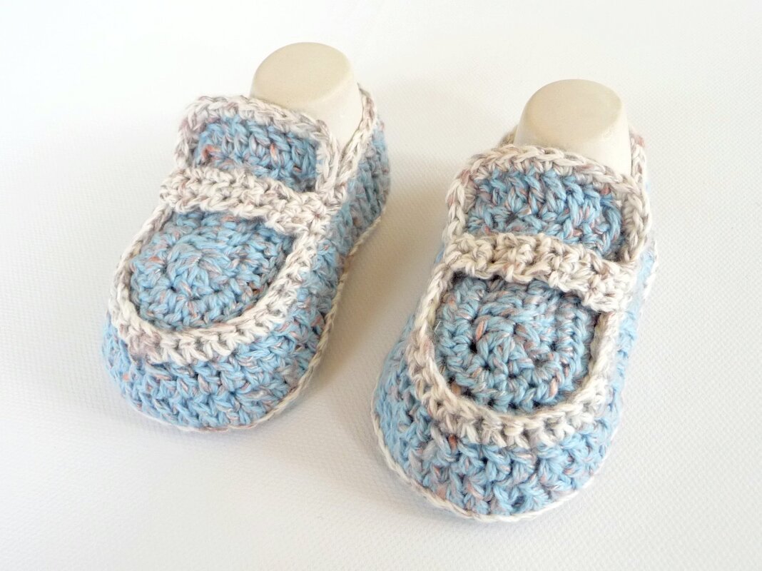 Gehäkelte hellblaue Babyschuhe mit Riemchen und kremfarbener Umrandung