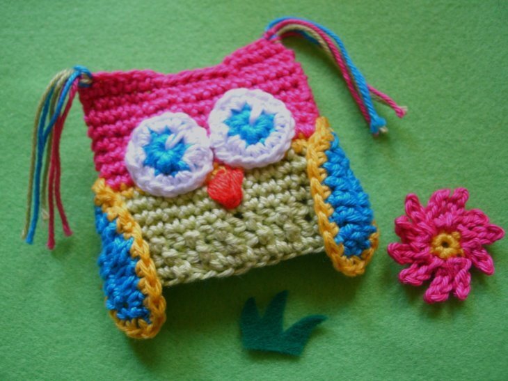 Bunte gehäkelte Eule als Eierwärmer mit großen Augen und orangefarbenem Schnabel auf grünem Filz