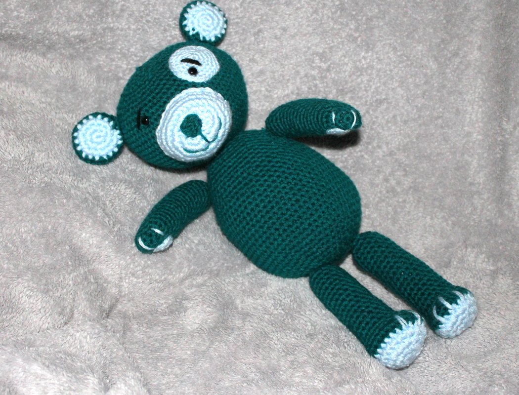 Gehäkelter Amigurumi-Teddybär dunkelgrün mit hellblauen Akzenten