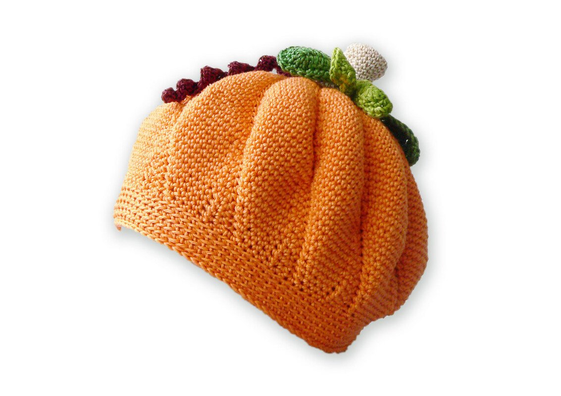 Orange crocheted taco-shaped hat with green, dark red, and cream yarn accents on a white background