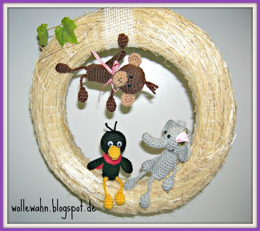 Strohkranz mit drei gehäkelten Amigurumi-Tieren: Affe, Vogel und Elefant