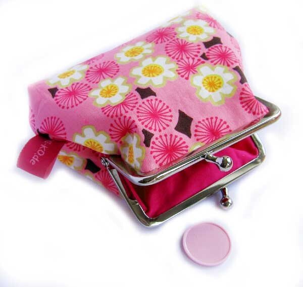 rosa Bügel-Geldbörse mit weiß-gelben Blüten, geöffnet, Metallbügelverschluss, Münze daneben