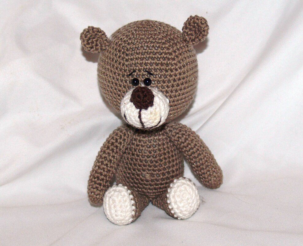 Gehäkelter brauner Teddybär mit weißer Schnauze und Pfoten, sitzend