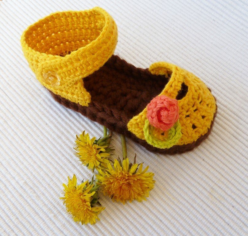 Gehäkelter gelb-brauner Babyschuh-Ballerina mit korallfarbener Blüte und Löwenzahn