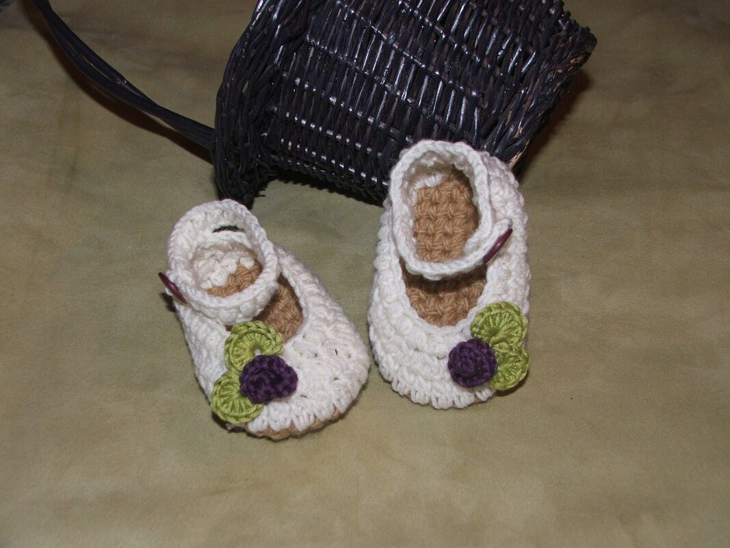Gehäkelte Babyschuhe mit Riemchen, beiger Innensohle und kleinen grünen und lila Blüten, Detailaufnahme