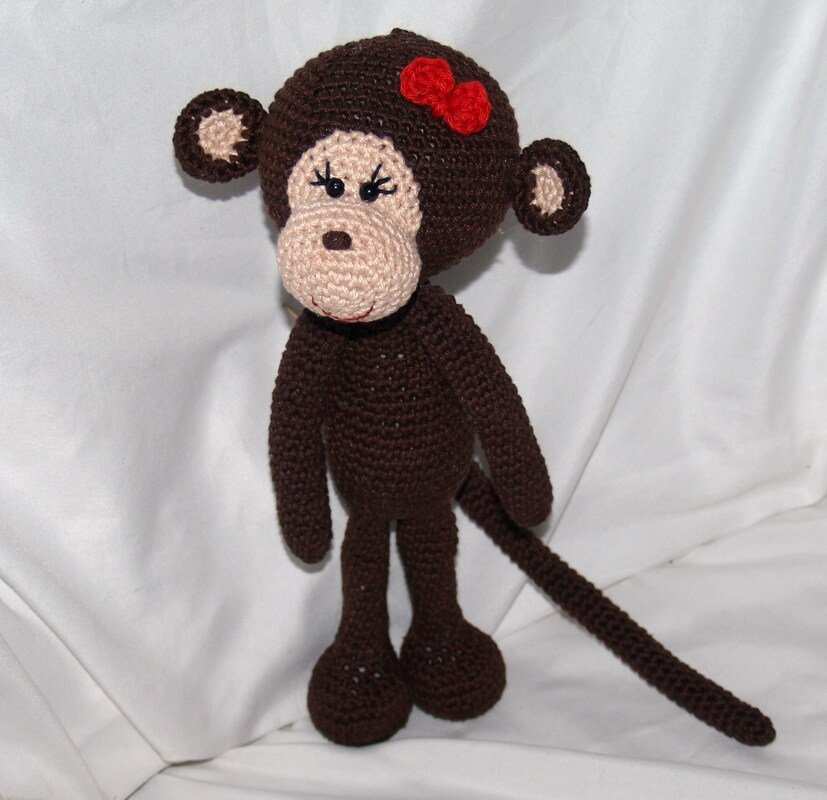 Gehäkelter brauner Amigurumi-Affe mit beiger Schnauze und roter Schleife