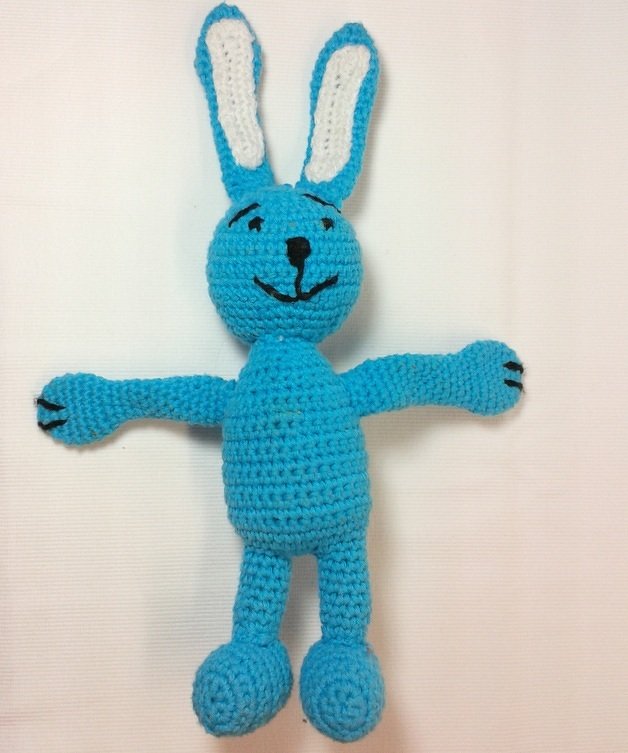 Türkisfarbener Amigurumi-Hase mit angenähten Armen und Beinen sowie gesticktem Gesicht