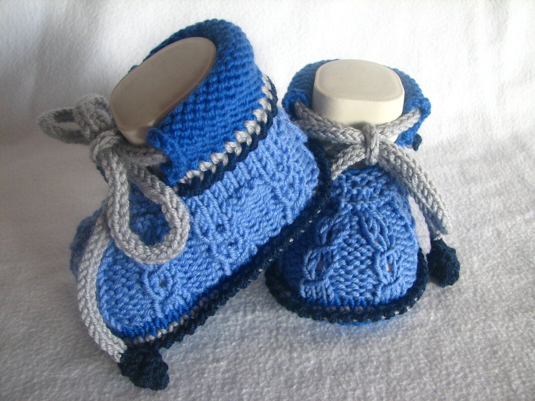 blaue Babyschuhe gestrickt mit grauen Schnürbändern und dunkler Sohle