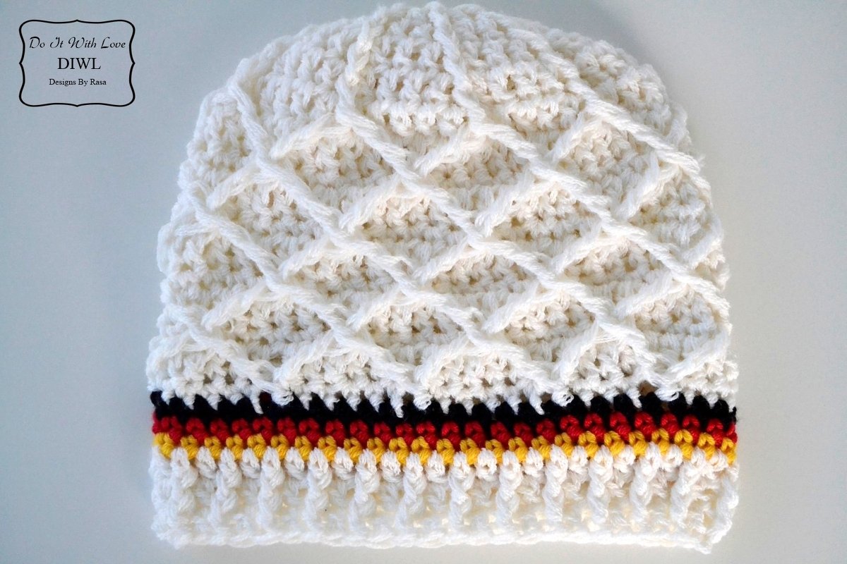 Cremeweiße gehäkelte Mütze mit erhabenem Rautenmuster und schwarzen, roten und gelben Streifen am Saum