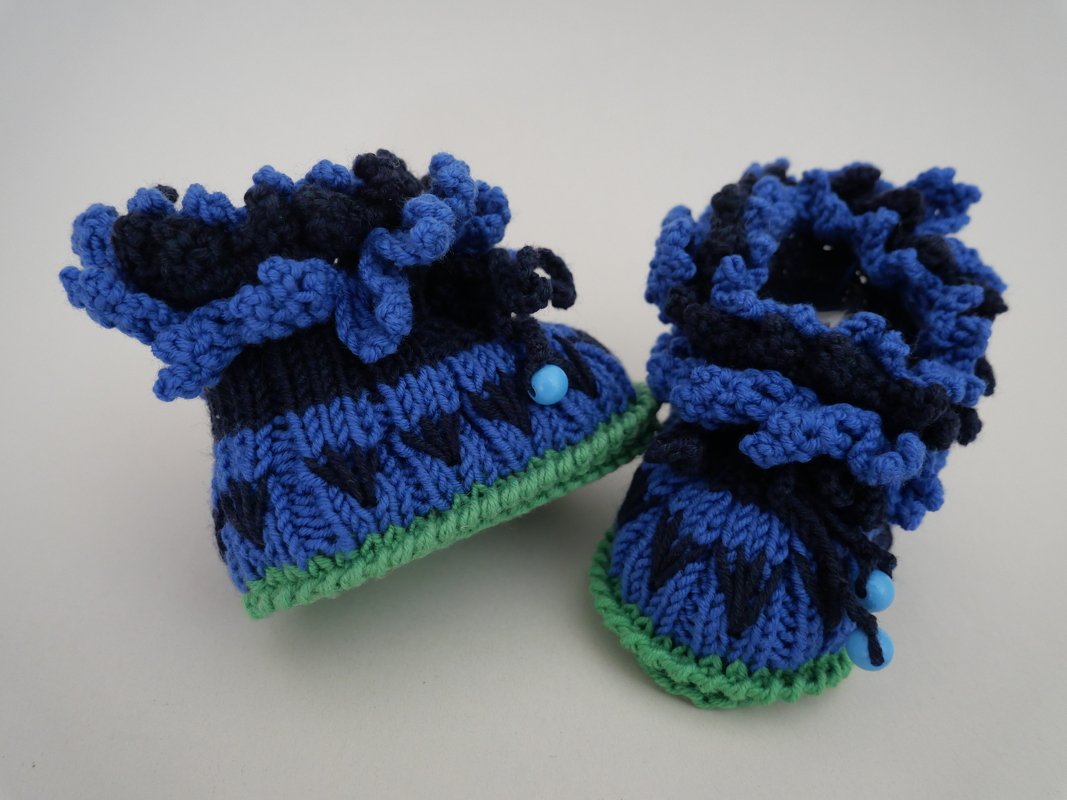 Blau-grüne gestrickte Baby-Booties mit auffälliger Rüschenmanschette und Perlendetail