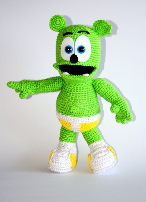 Grünes gehäkeltes Amigurumi mit großen Augen und weißen Schuhen