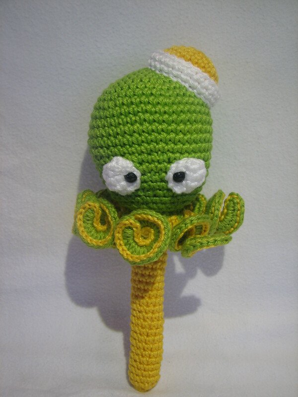 Grüne gehäkelte Baby-Rassel in Oktopusform mit gelbem Griff