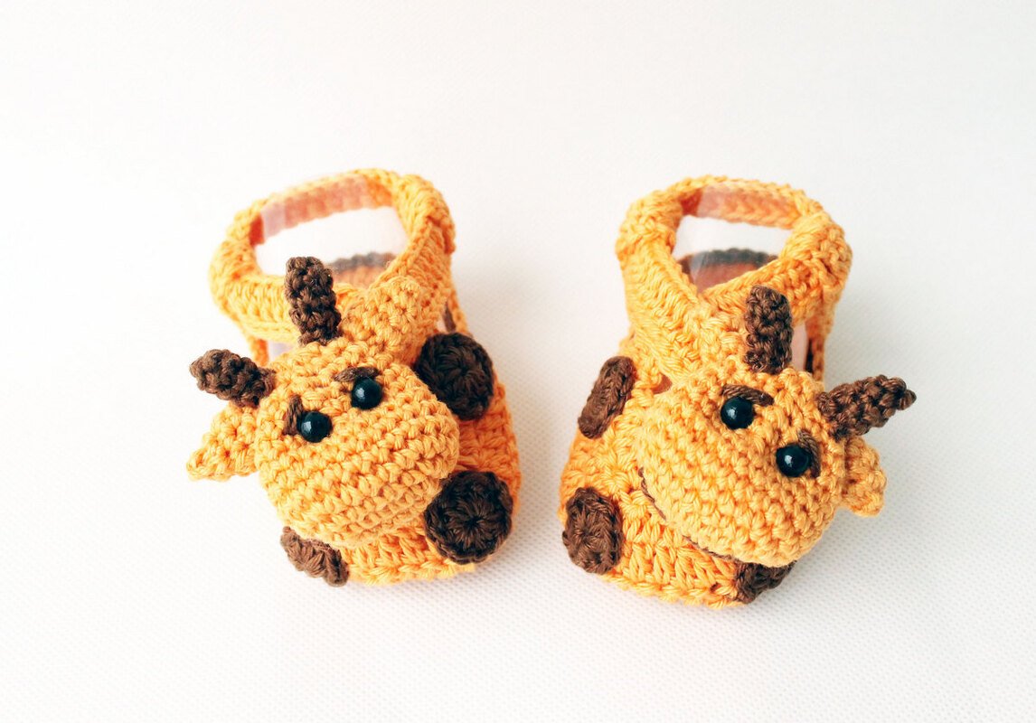 Gelb-orange gehäkelte Babyschuhe mit Giraffen-Applikationen, Riemchen und braunen Flecken