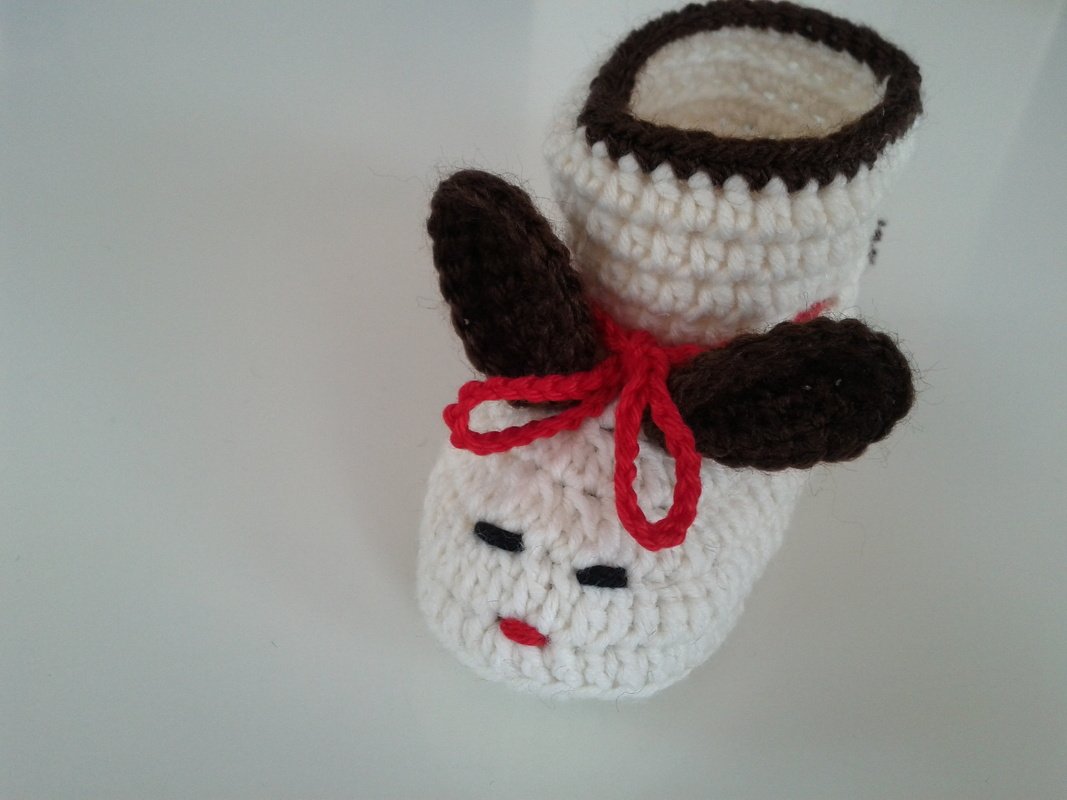 Weiß-brauner gehäkelter Babyschuh mit Ohren und roter Kordel