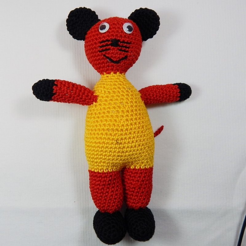 Gehäkelte Amigurumi‑Maus in Rot und Gelb mit schwarzen Akzenten, stehend