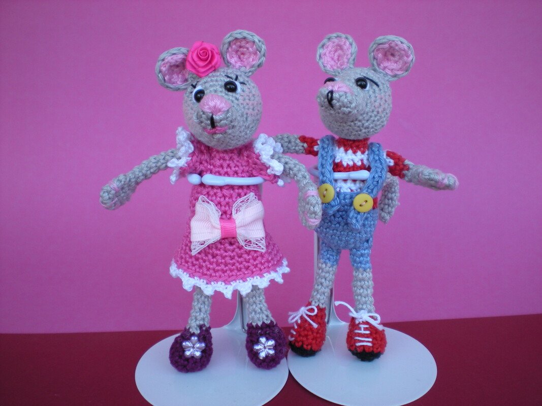 Gehäkeltes Amigurumi‑Mäusepaar: Mädchen in Rosa und Junge in Blau vor rosa Hintergrund