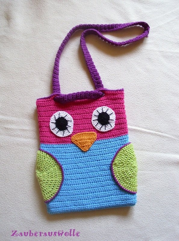 Gehäkelte Eulen-Henkeltasche in Pink, Blau und Grün mit lila Tragegurt auf hellem Hintergrund