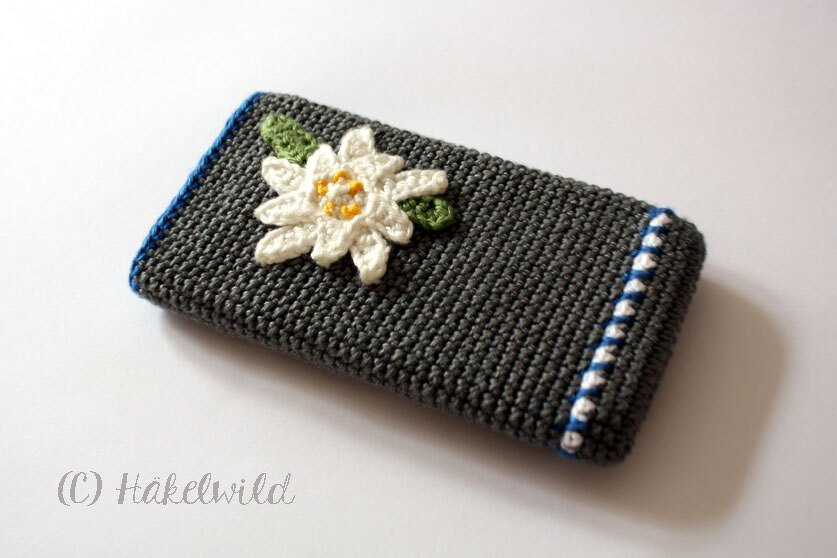 Grau gehäkelte Handytasche mit weißer Edelweiß-Applikation und blauer Zierkante