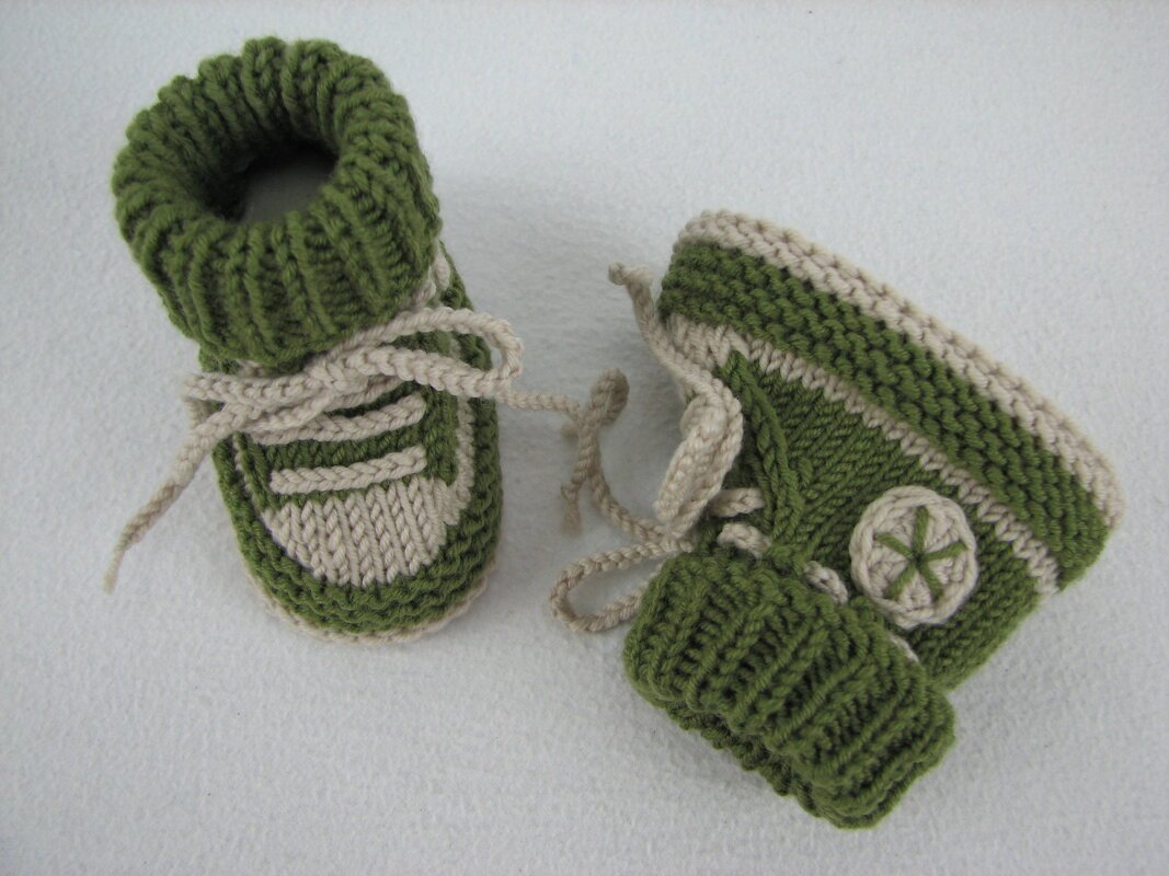 Detaillierte Ansicht zweier grüner-beiger gestrickter Babyschuhe mit Schnürsenkeln