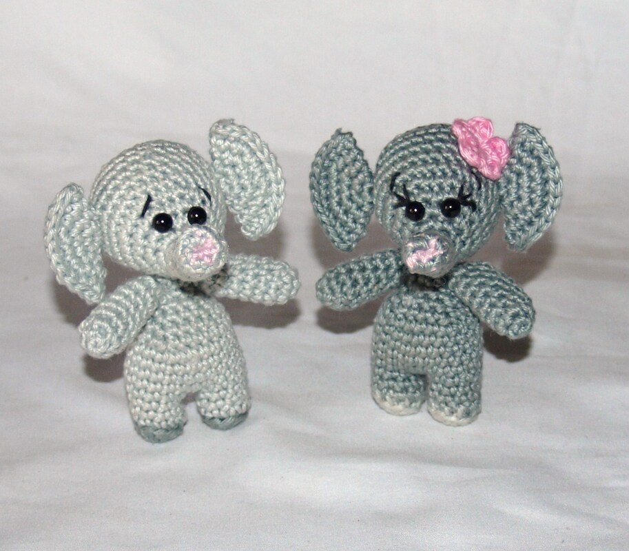 Zwei gehäkelte Amigurumi-Elefanten, hellgrau und dunkelgrau mit rosa Schleife