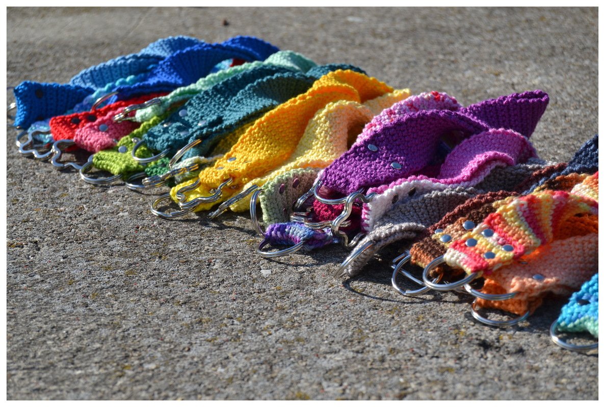Gehäkelte Schlüsselanhänger in Regenbogenfarben mit Metallringen auf Asphalt