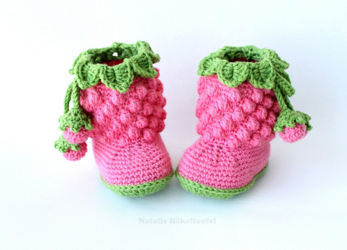 Gehäkelte rosa Babyschuhe mit grünem Blattkragen und Beerenanhängern