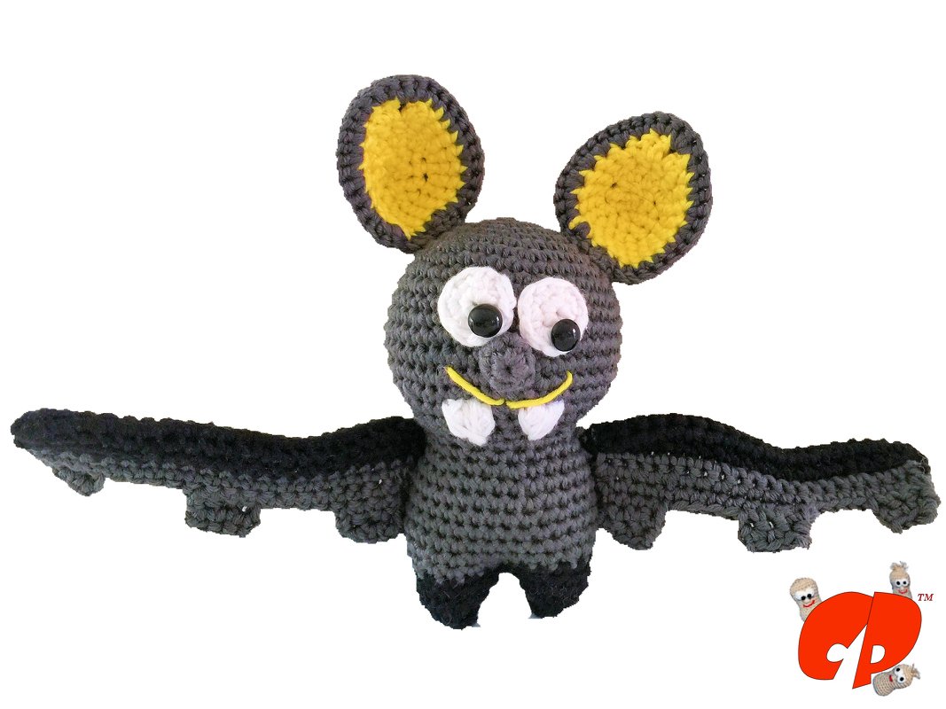Grau-gelbe gehäkelte Fledermaus-Amigurumi mit ausgestreckten Flügeln und weißen Augen