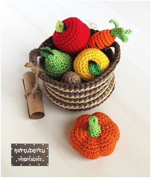 Handgehäkelter Korb mit buntem Obst und Gemüse sowie einem orangefarbenen Kürbis.