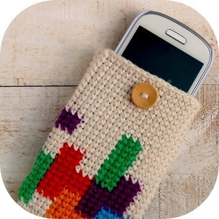Häkelhülle für Smartphone mit farbigen Pixelblöcken und Holzknopf