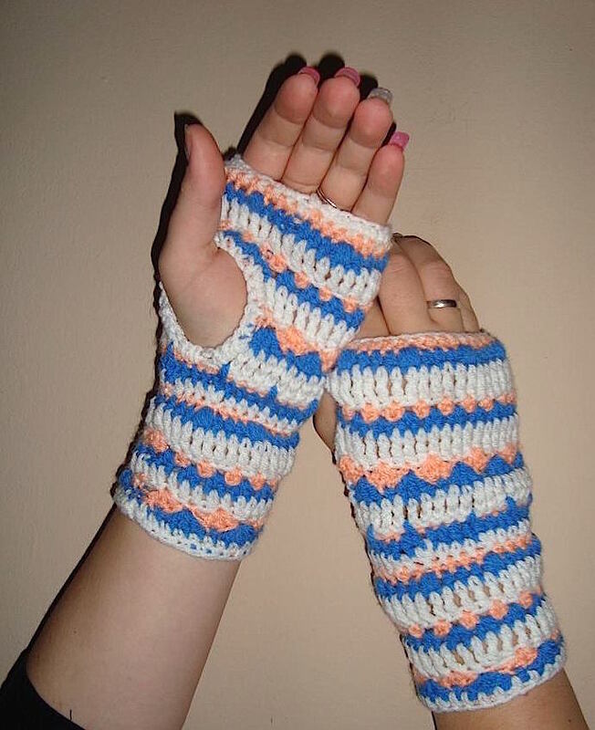 Detailaufnahme gehäkelter fingerloser Handschuhe mit Daumenloch und Streifen in Blau Weiß Pfirsich
