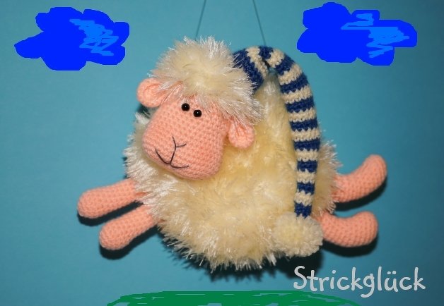 Beiges gehäkeltes Amigurumi‑Schaf mit rosafarbenem Kopf und blau-weiß gestreifter Schlafmütze vor hellblauem Hintergrund.