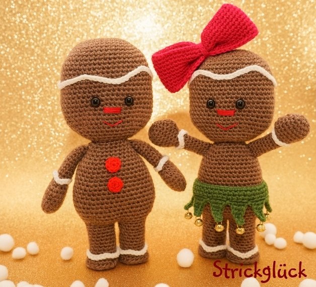 Zwei gehäkelte Lebkuchen-Amigurumi mit weißen Zierlinien, roter Schleife und grünem Röckchen vor goldenem Hintergrund