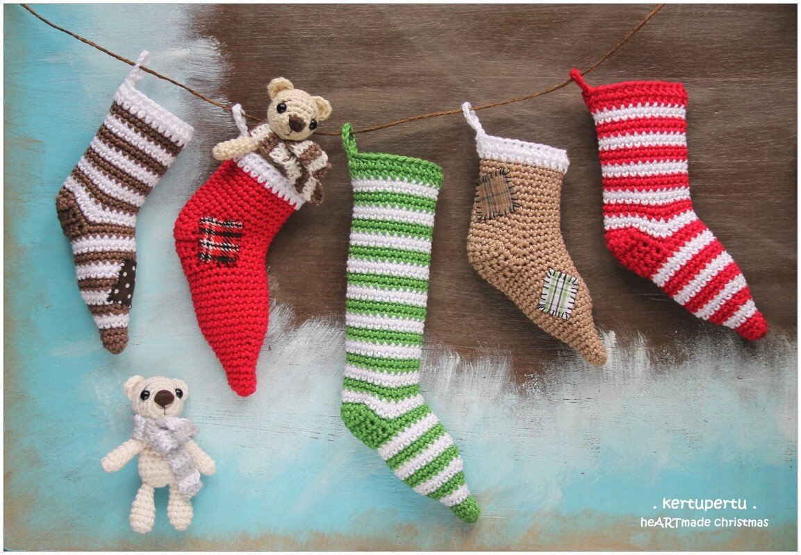 Fünf gehäkelte Weihnachtsstiefel an einer Schnur, zwei kleine Amigurumi-Bären, rustikaler türkis-brauner Hintergrund