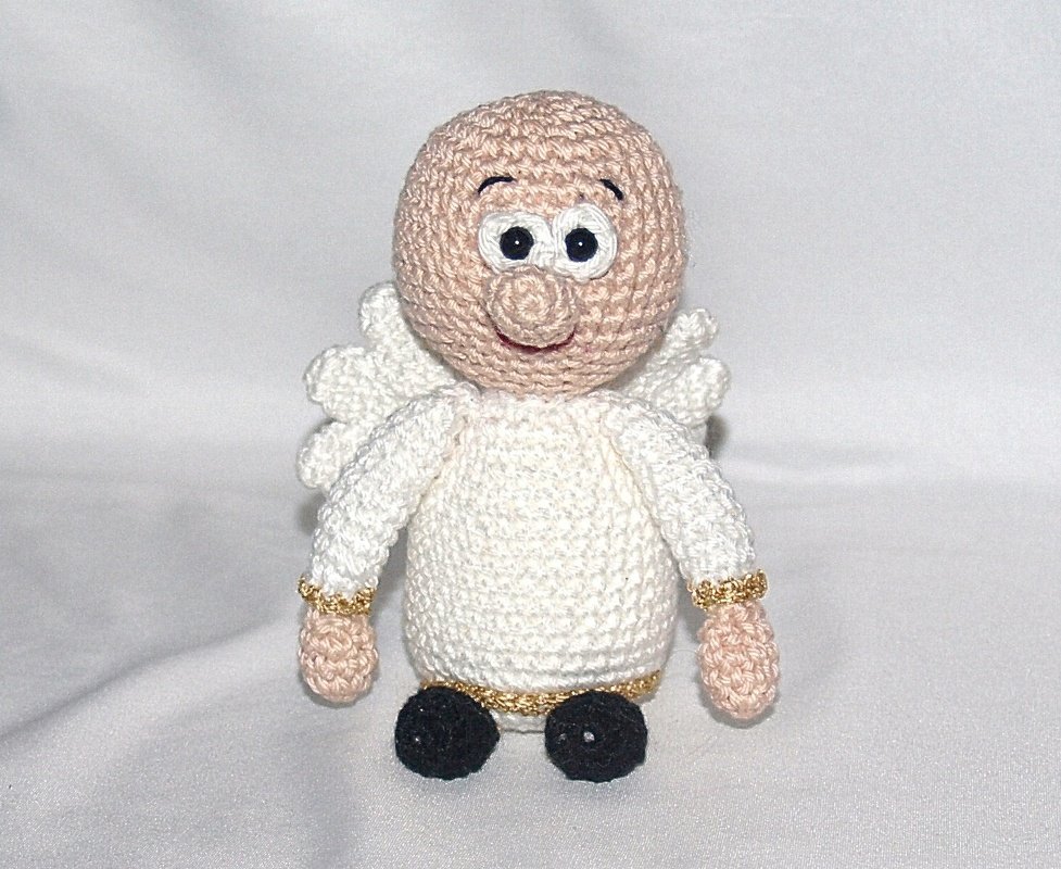 Gehäkeltes Engelchen Amigurumi in Weiß mit goldenen Zierfäden, beigem Kopf und schwarzen Schuhen