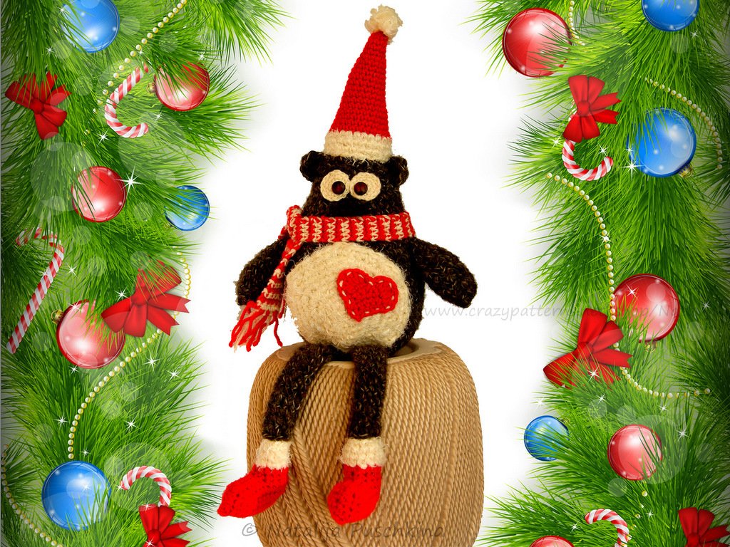 Sitzende Amigurumi-Eule mit roter Mütze, gestreiftem Schal und Herzapplikation auf Garnrolle