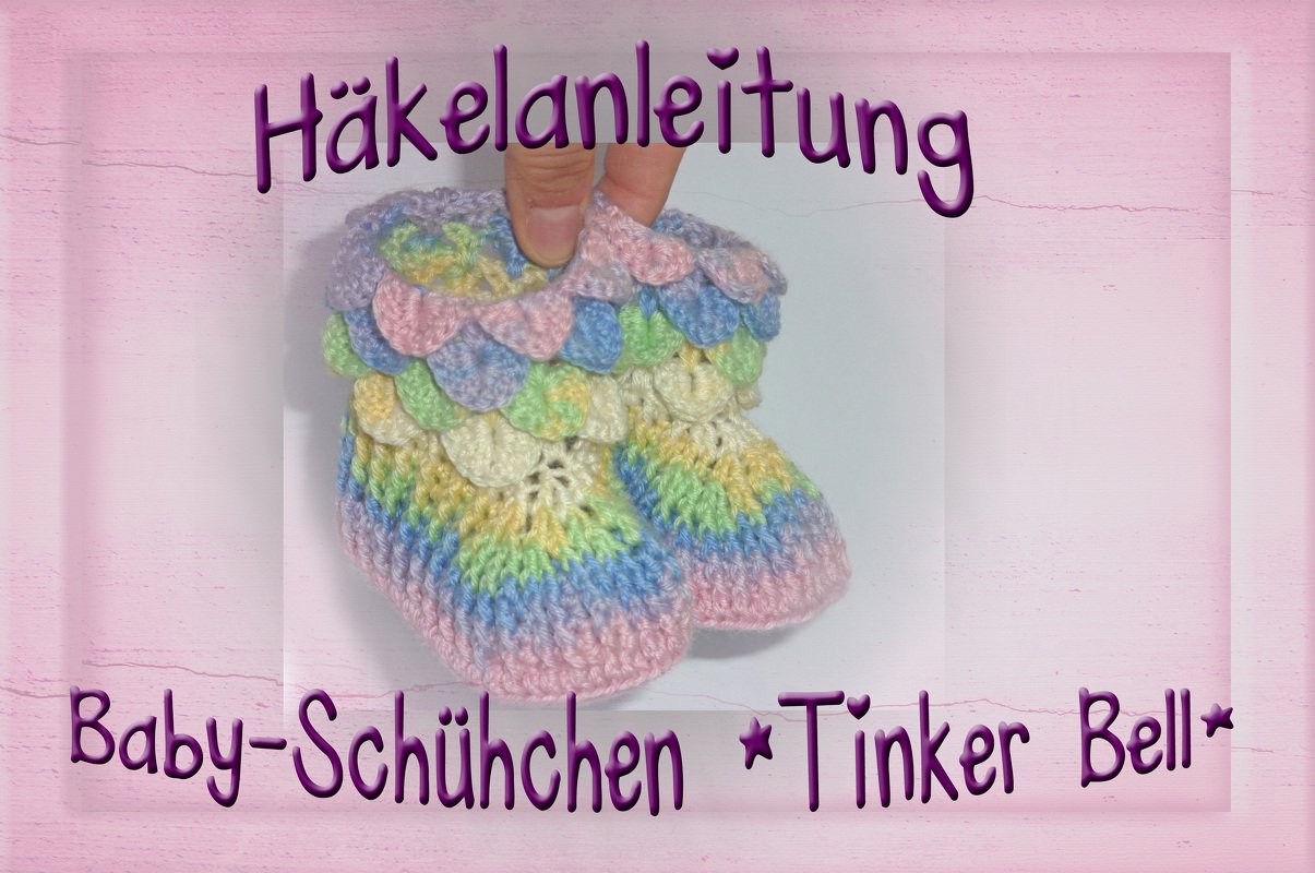 Zwei kleine gehäkelte Booties in Pastellfarben mit Muschelsaum, gehalten von einer Hand