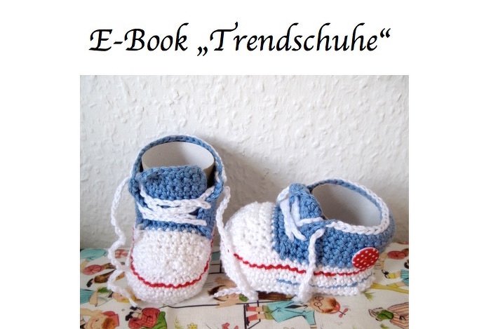 Gehäkelte Babysneaker in Blau und Weiß mit roten Akzenten und weißen Schnürsenkeln