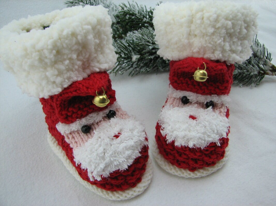 Rote und weiße gestrickte Babyschuhe mit Weihnachtsmann-Gesicht und goldener Glocke