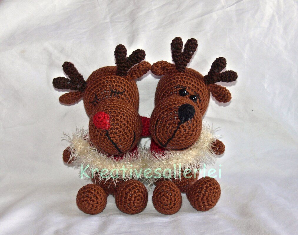 Zwei braune gehäkelte Rentier-Amigurumi nebeneinander, links mit roter Nase, rechts mit schwarzer Nase, beide mit Geweihen und flauschigem Kragen