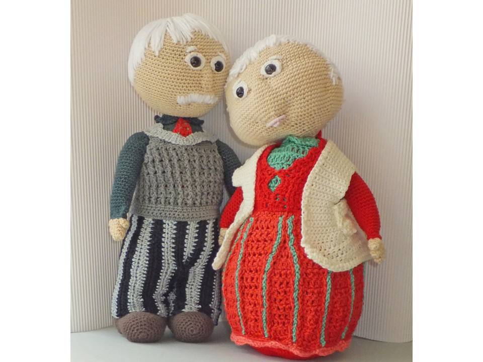 Gehäkeltes Amigurumi-Seniorenpaar: Mann mit Schnurrbart, grauer Weste und gestreifter Hose; Frau in rotem Kleid und cremefarbener Weste.