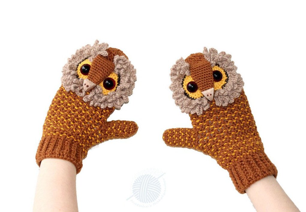 Gehäkelte Eulen‑Fäustlinge in Braun und Gelb, an Händen getragen vor weißem Hintergrund